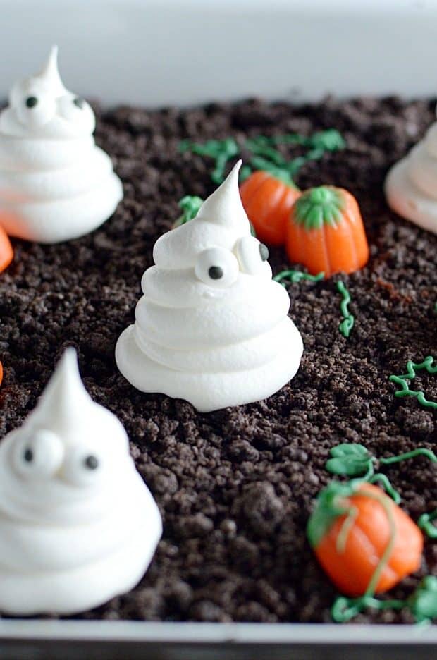 Spooky and cute Halloween cake made with Oreo crumbs, Cool Whip ghosts, and candy corn pumpkins!