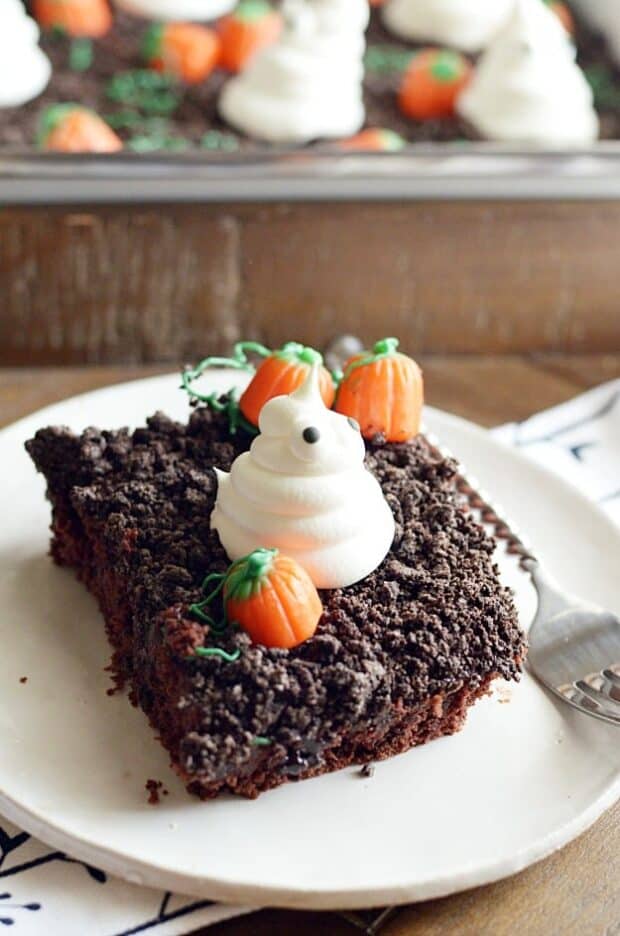 Spooky and cute Halloween cake made with Oreo crumbs, Cool Whip ghosts, and candy corn pumpkins!